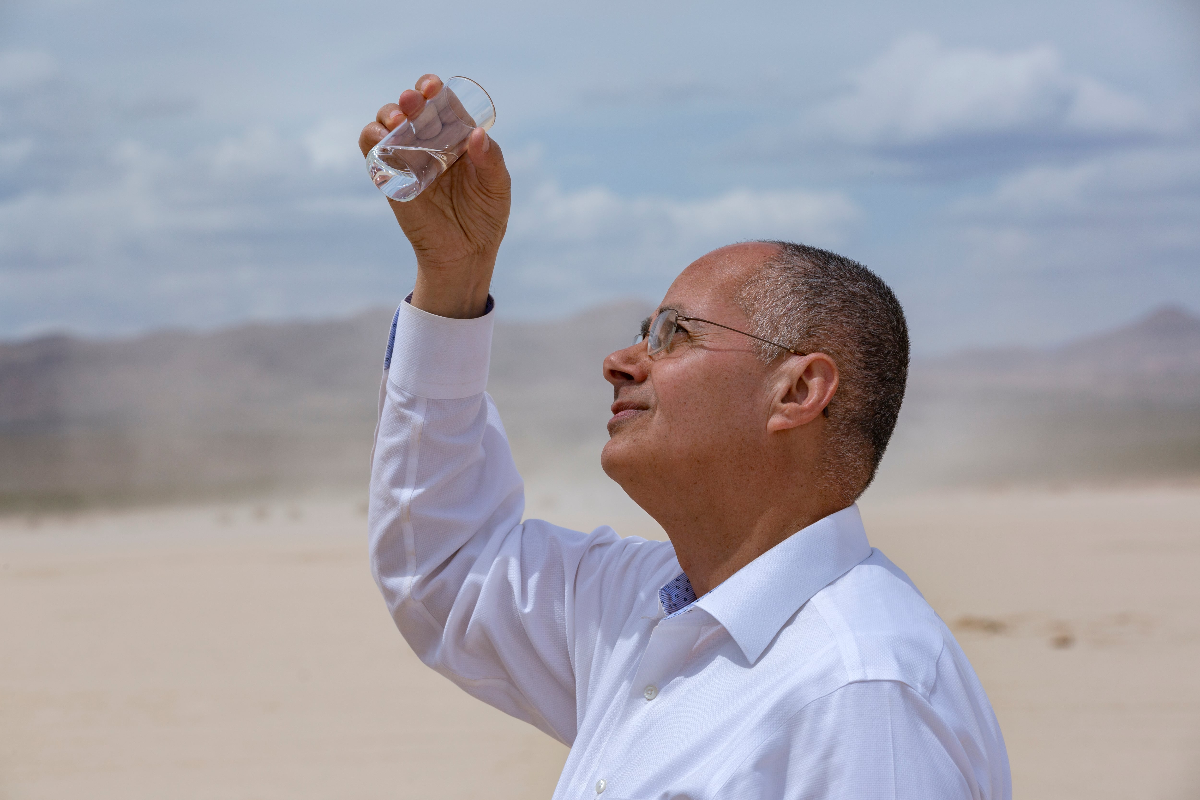 Prof Omar Yaghi holding up glass with water in Death Valley