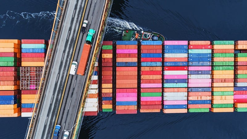 A cargo ship that is going under a bridge