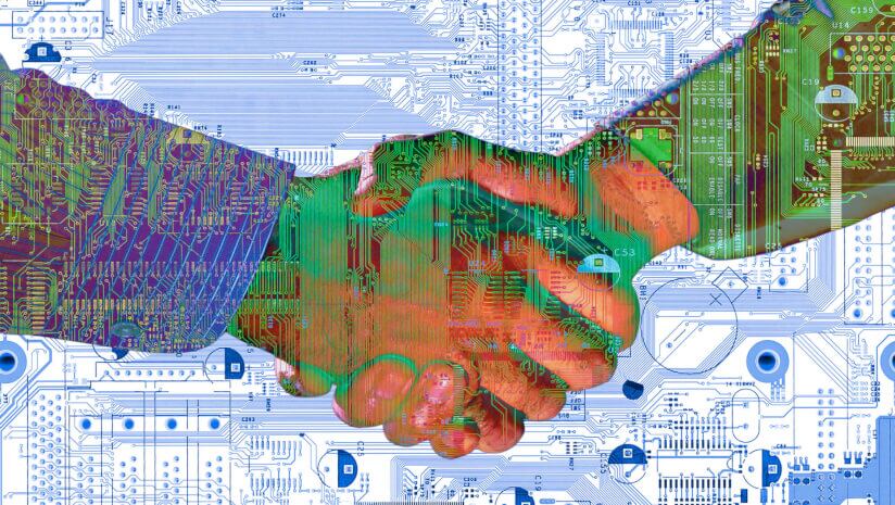 Two hands shaking in tech environment