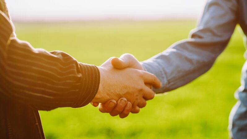 Two people shaking hands on a farm.